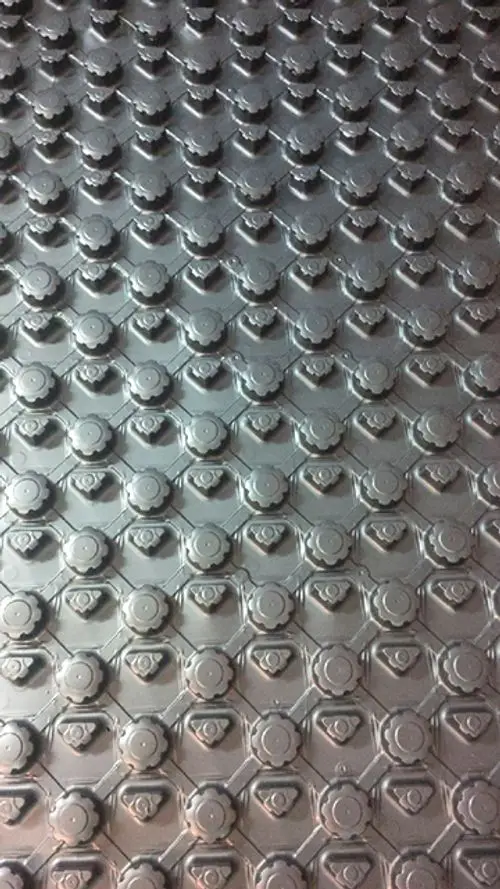 Oberfläche einer Systemplatte von Daikin mit hexagonalem Muster und runden Erhöhungen, gefertigt aus Metall, in grauer Farbgebung.